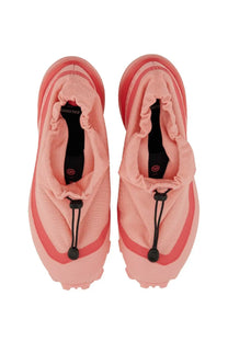 Pink salomon running shoes with soft stretchy fabric upper and bold red accents in mm6 maison margiela women’s sneaker