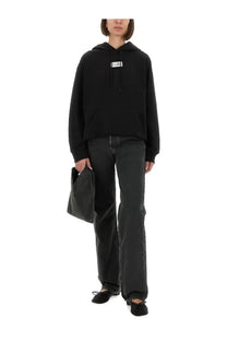 Black oversized cotton hoodie for women by MM6 Maison Margiela with a white rectangular logo patch on the chest