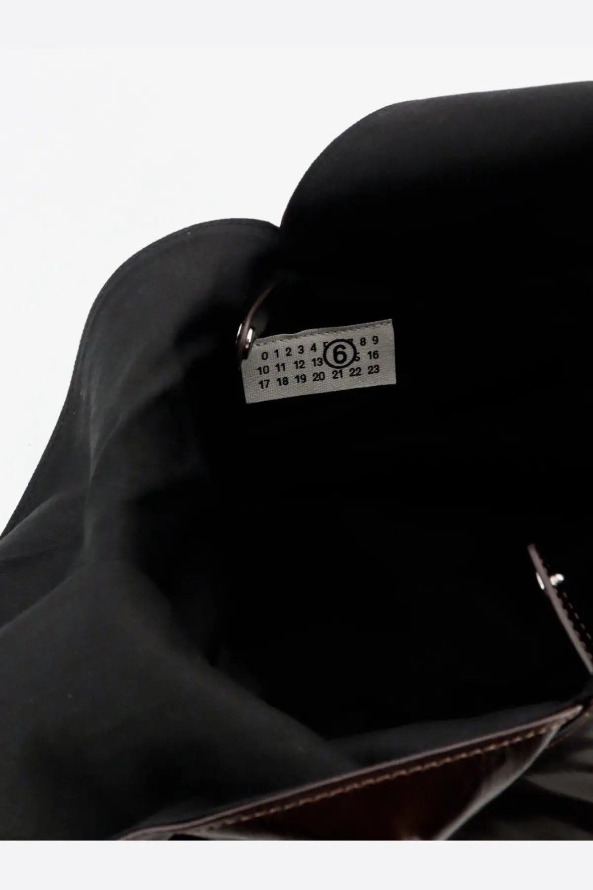 Black fabric interior with white label showing black printed numbers and circled 6 in mm6 maison margiela japanese leather bag