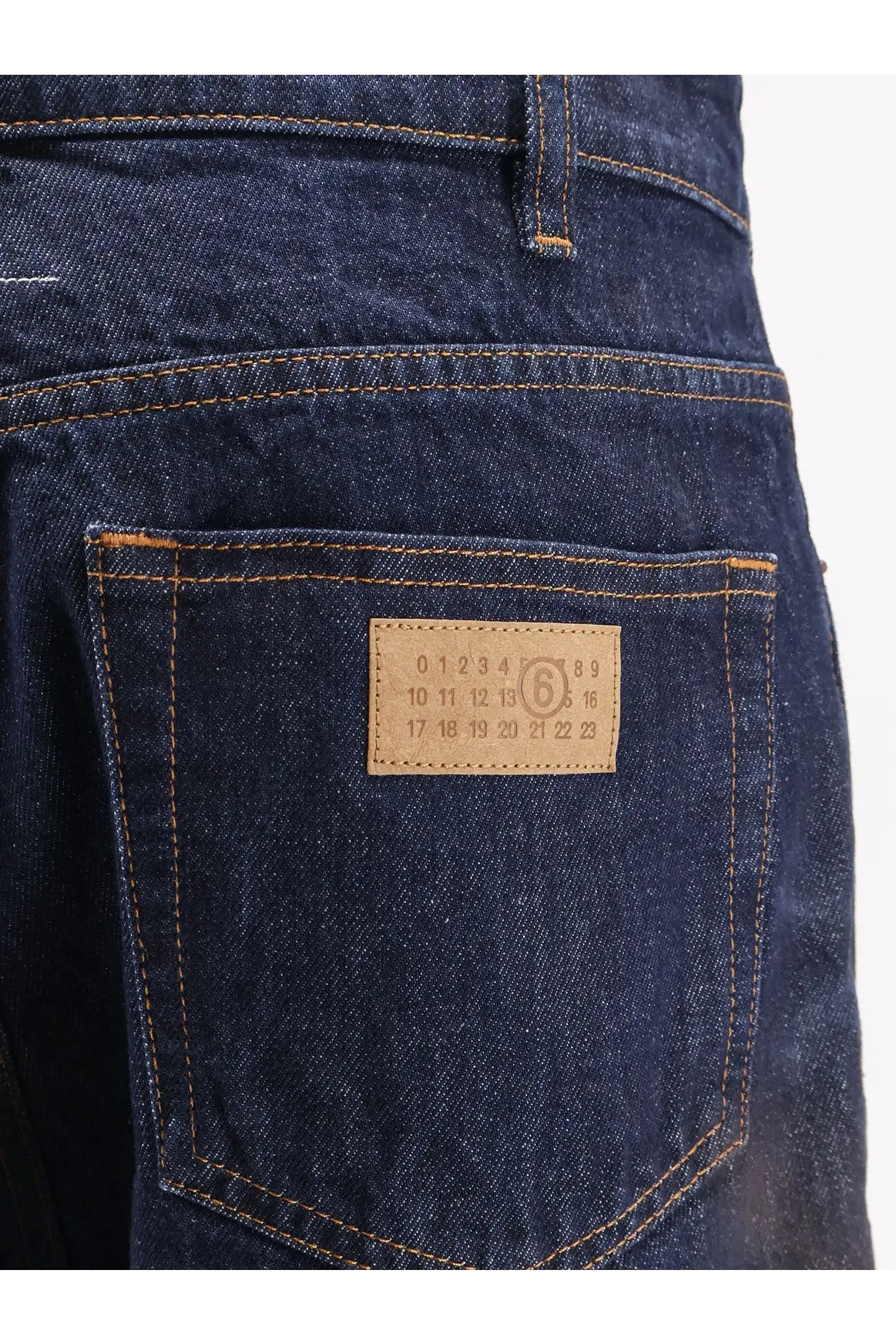 Dark blue denim jeans with tan leather patch featuring printed numbers and number 6 in a circle by mm6 maison margiela