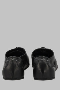 Back view of mm6 maison margiela womens stringata black leather dress shoes with white stitching along the back