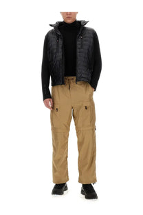 Black quilted puffer vest with hood and front zipper worn over black turtleneck with moncler grenoble beige cargo pants