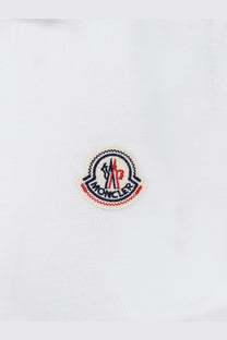 White moncler logo patch with red and navy blue embroidery on white fabric of men’s cotton polo shirt