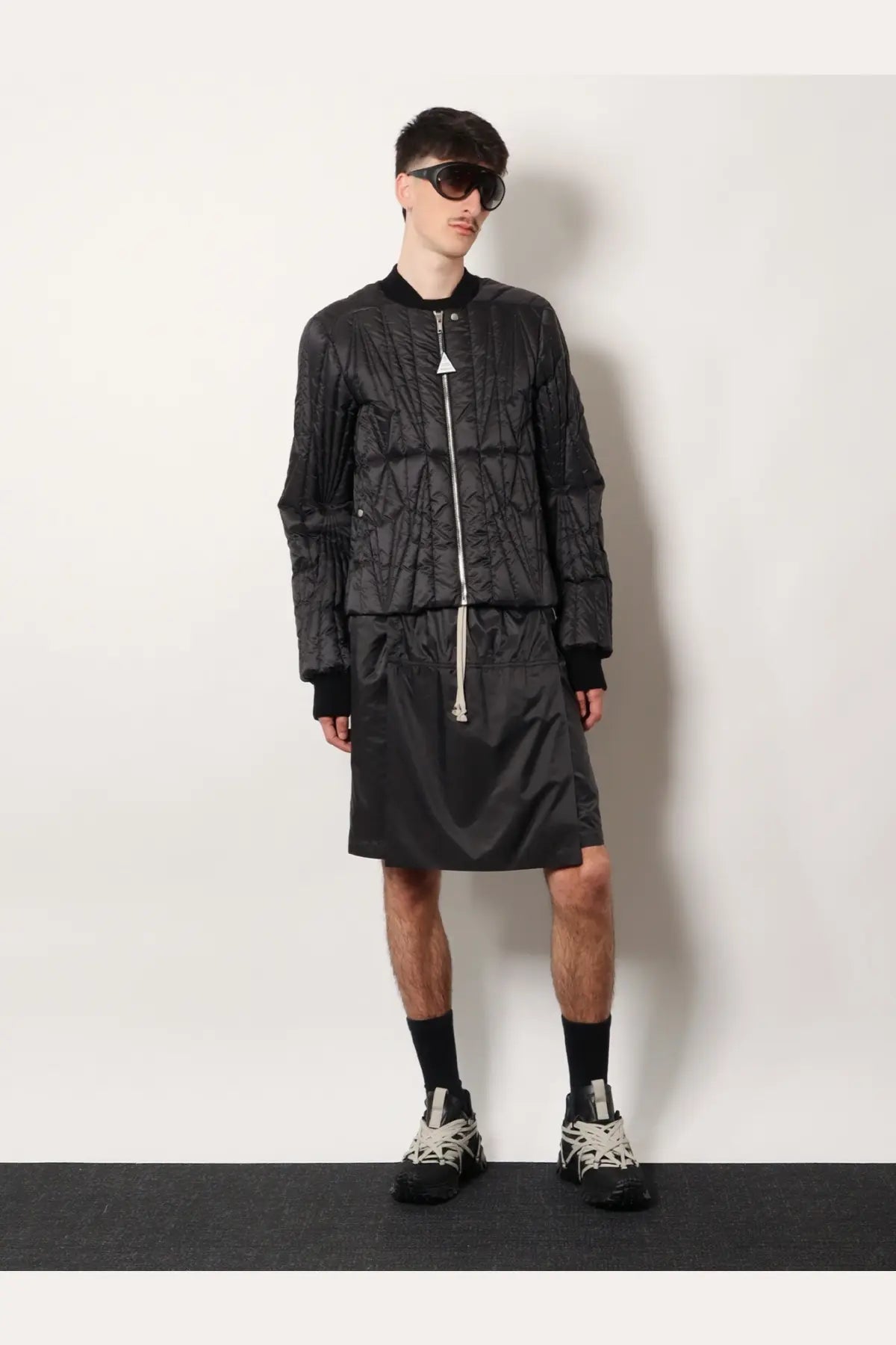 Black quilted bomber jacket with white zipper and triangular logo at collar from moncler and rick owens