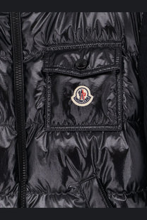 Moncler women’s black down jacket with glossy quilted texture and circular logo patch on chest pocket