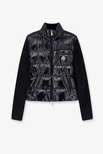 Moncler women’s black down jacket with quilted body, solid knit sleeves, front zipper, and chest pocket patch