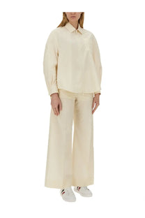 Cream-colored loose-fitting cotton blouse with classic collar and long sleeves paired with moncler white poplin pants