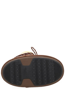 Brown suede moon boot with black rubber sole featuring circular and ribbed traction patterns for women