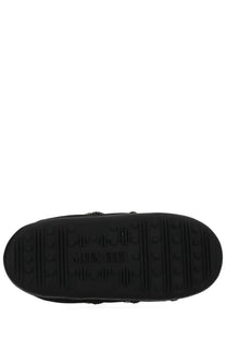 Black rubber sole of moon boot women’s soft slipper shoe beige with embossed branding and textured tread pattern