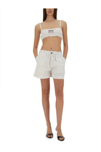 White cotton cropped top with thin straps and small rectangular patch paired with moschino jeans white shorts