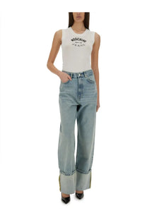 High-waisted light blue denim jeans with rolled cuffs and subtle gold trim styled with Moschino white knit top