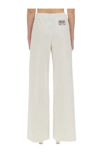 Back view of cream-colored moschino jeans wide leg pants with drawstring waistband and brand patch on the pocket