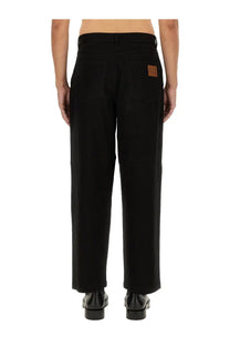 Back view of moschino men’s barcode black wide-leg trousers with brown leather patch on the right pocket