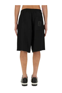 Back side of moschino men’s bermuda black athletic shorts with elastic waistband and rectangular patch on pocket