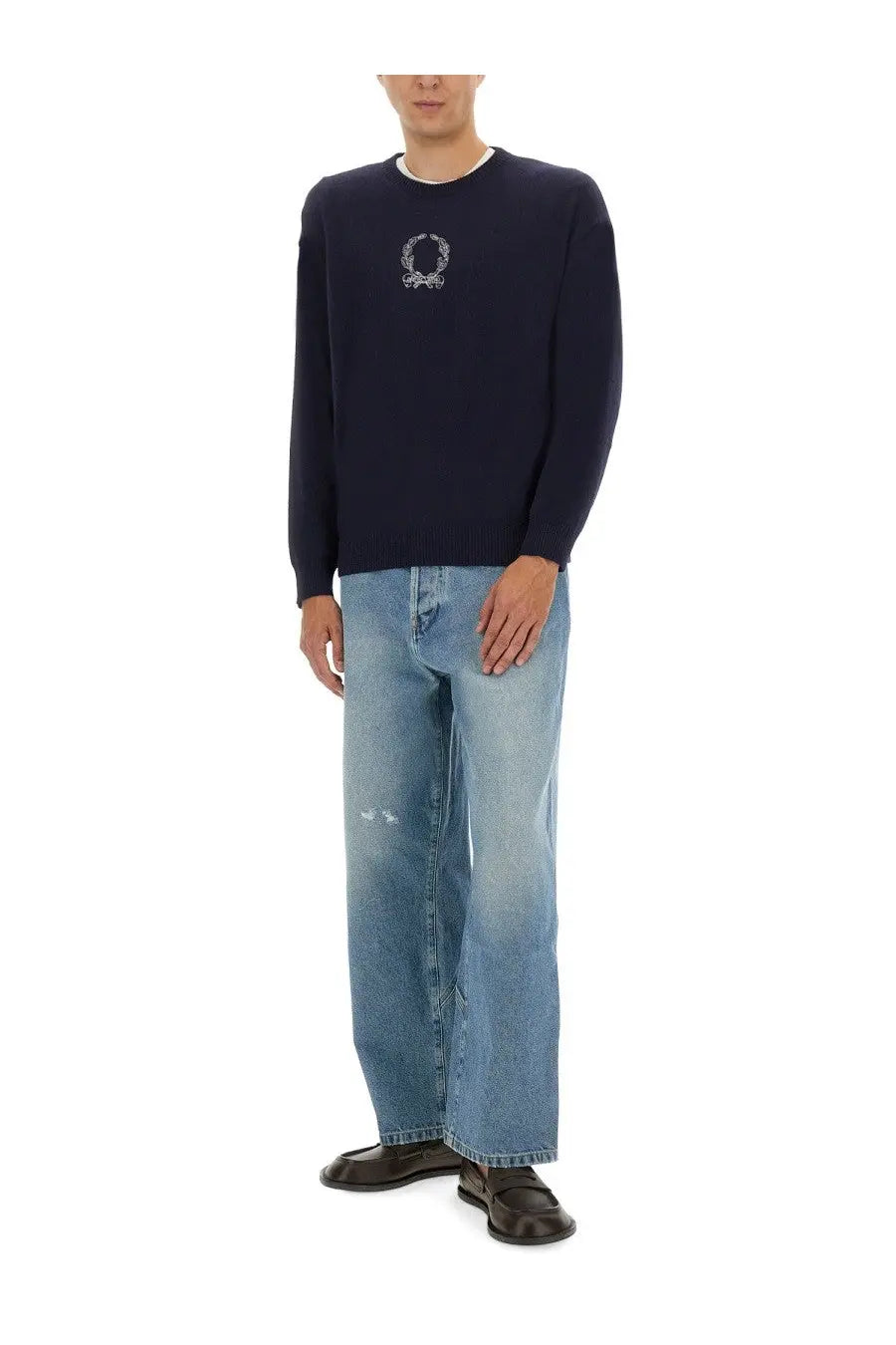 Navy blue knit sweater with white embroidered laurel wreath emblem paired with moschino men’s cotton denim jeans blue