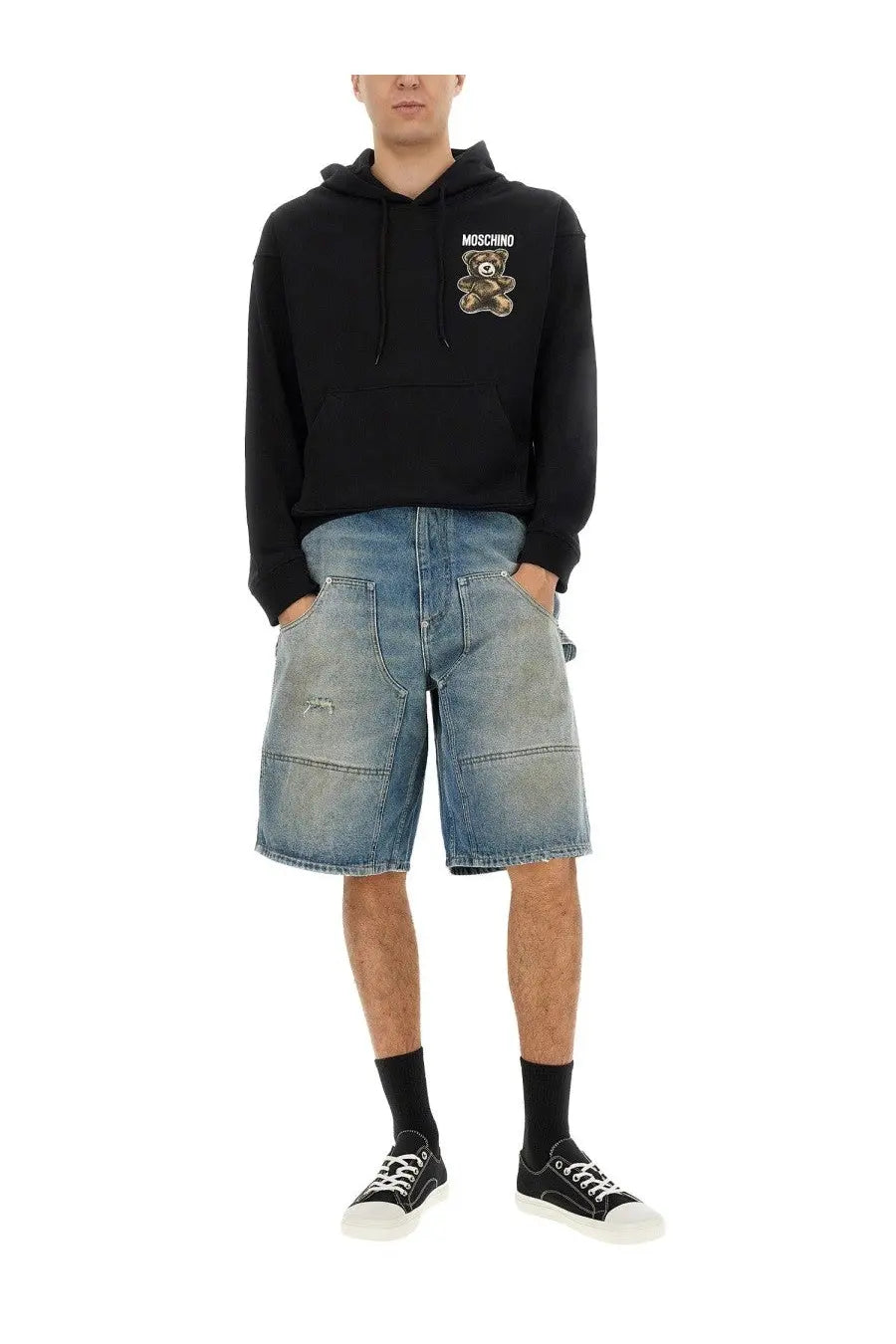 Black Moschino hoodie with embroidered teddy bear patch on chest paired with men’s blue denim shorts