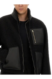 Moschino men’s black shearling jacket with black leather patches and gold zippers shown from the front