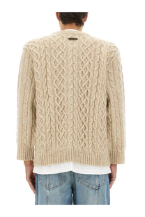 Moschino men’s beige cable knit sweater with ribbed hem and cuffs featuring a dark tag at the neckline
