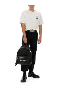 Black Moschino couture backpack with silver zippers and front pocket featuring white logo paired with Moschino men’s white shirt