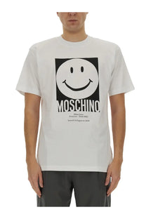 Moschino men’s white cotton t-shirt featuring a bold black smiley face logo with the brand name printed below