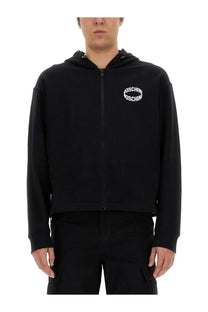 Moschino men’s black zip-up hoodie with white circular logo on chest made from soft cotton blend material