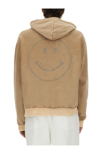 Beige suede Moschino men’s hoodie with smiling face silver studs and chain detailing on the front