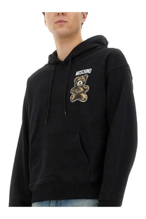 Moschino men’s black hoodie featuring a brown embroidered teddy bear graphic on the chest