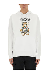 Moschino men’s white cotton hoodie with teddy bear print for fun text and rainbow ribbon detail on front