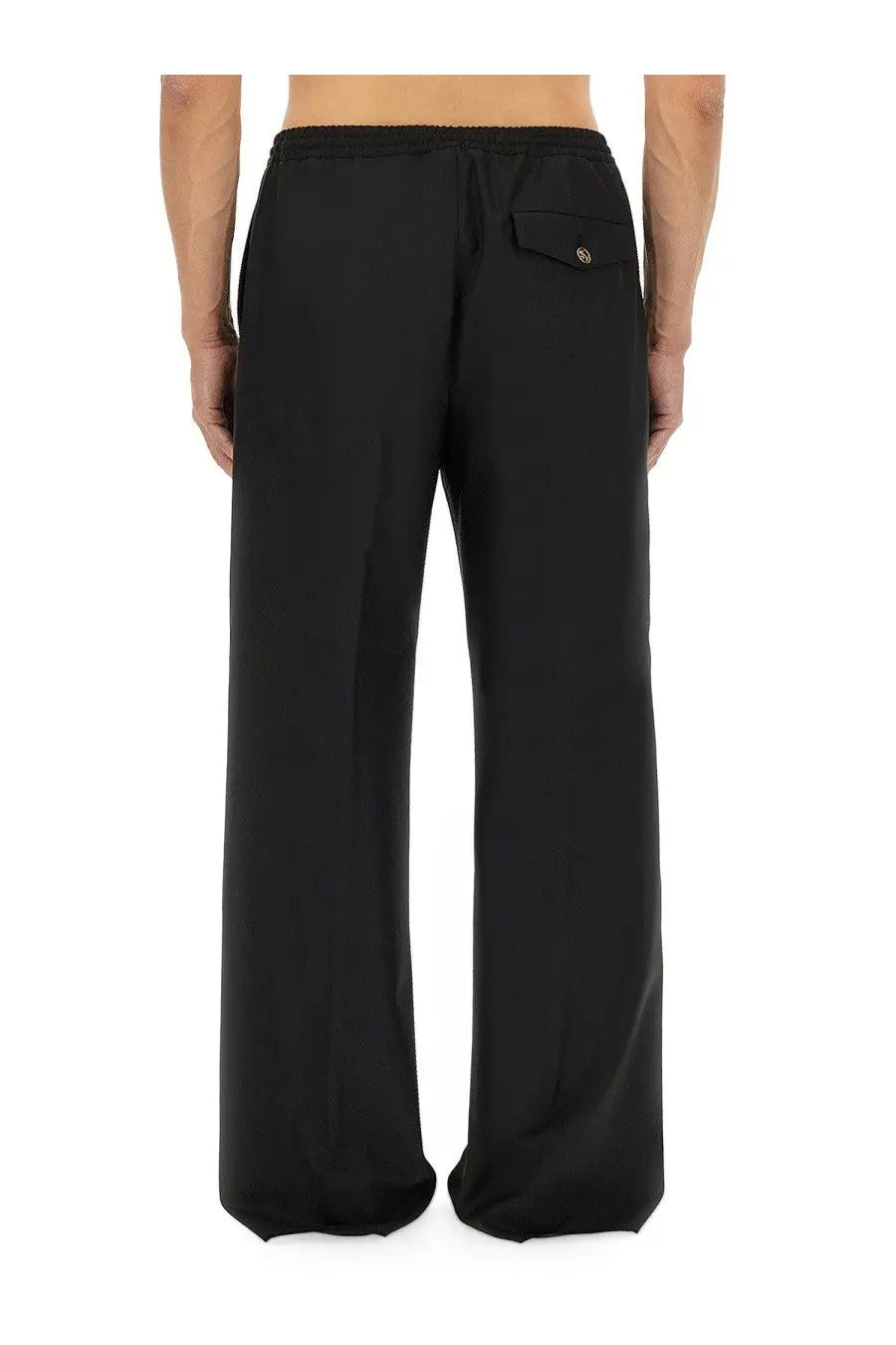 Back view of moschino men’s black wool canvas pants featuring wide legs, drawstring waistband, and one buttoned pocket