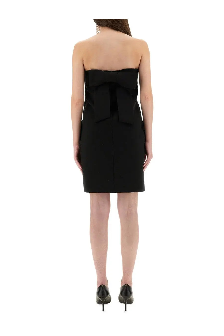 Back view of moschino women’s black bandage sheath mini dress with strapless design and prominent bow detail