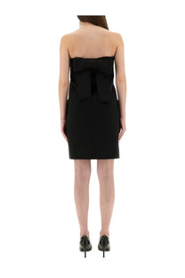 Back view of moschino women’s black bandage sheath mini dress with strapless design and prominent bow detail
