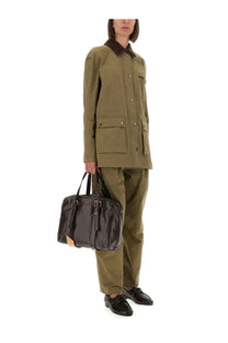 Black patent leather briefcase with tan leather accents and silver hardware paired with moschino women’s green heavy cotton jacket