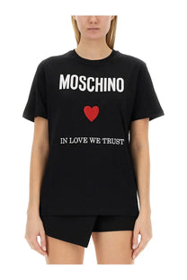 Moschino women’s black t-shirt with white moschino lettering red heart emblem and in love we trust phrase printed below