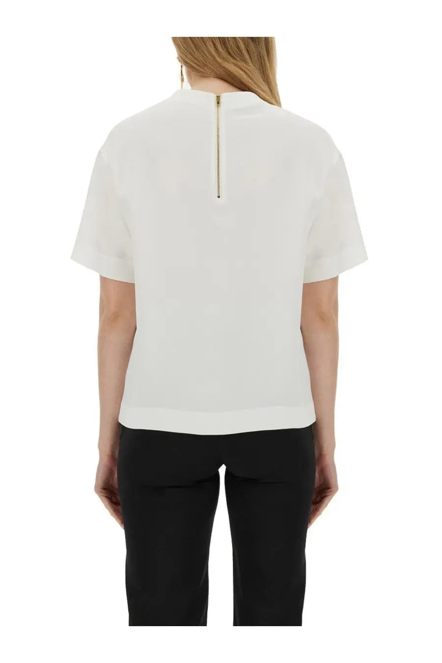 White short-sleeved moschino blouse with subtle sheen and gold zipper at back neckline showcasing the back side
