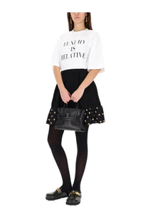 Black leather handbag with gold-tone hardware and structured rectangular shape featured with Moschino women’s shirt white