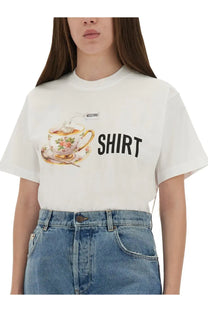 Moschino women’s white t-shirt featuring an ornate floral teacup illustration with gold trim and bold black shirt lettering