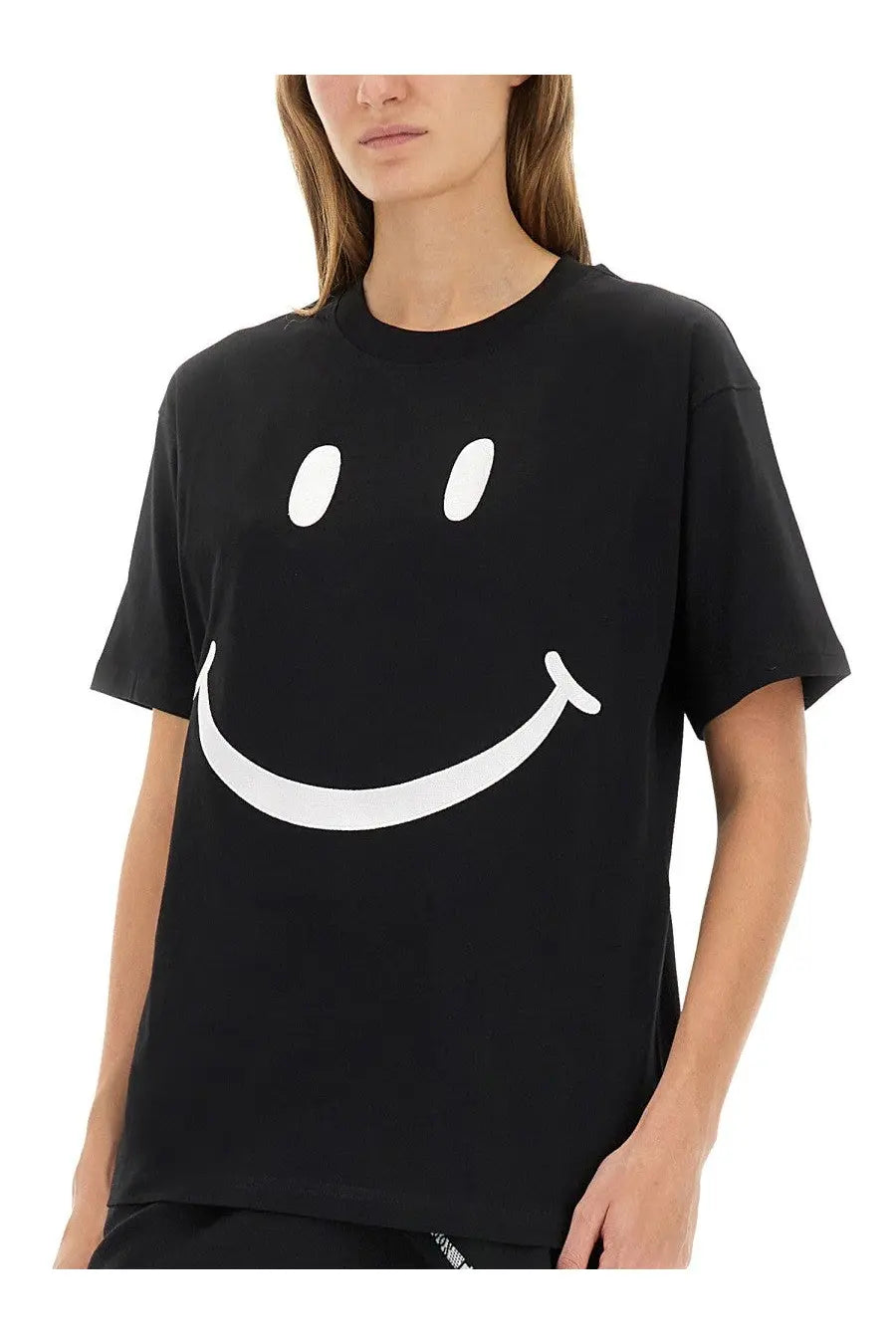 Moschino women’s black short-sleeved cotton t-shirt featuring a large white smiley face graphic on the front