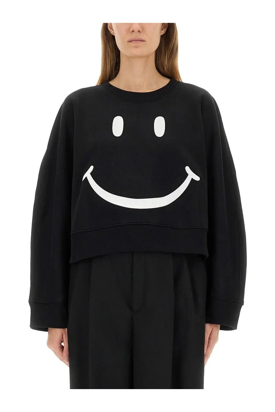 Moschino women’s black cropped sweatshirt made of soft fabric featuring a large white smiley face graphic on front
