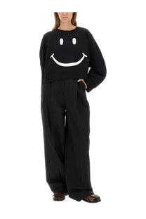 Moschino women’s black cropped sweatshirt made of cotton featuring a large white smiley face graphic on the front