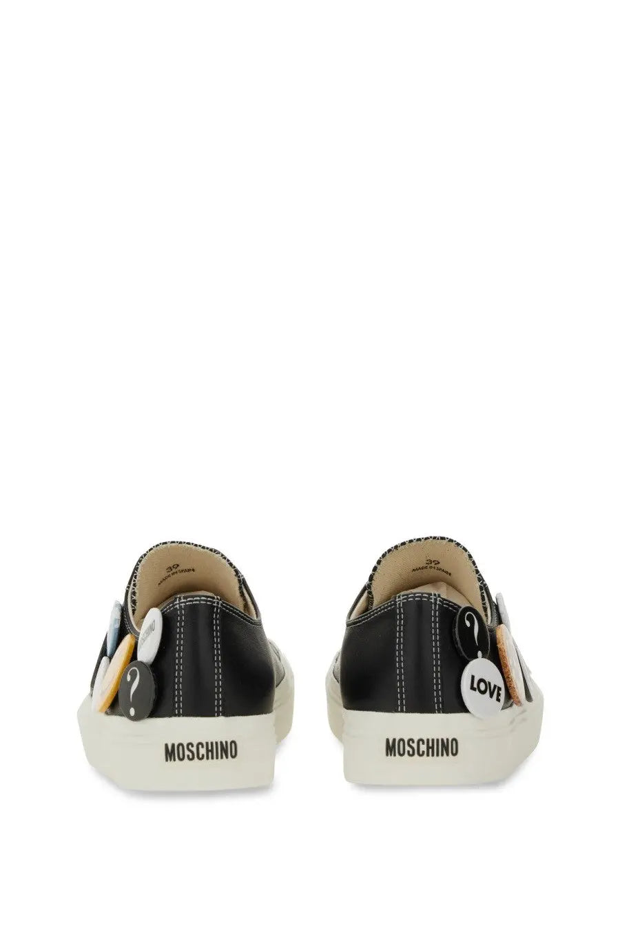 Moschino women’s black slip-on sneakers with white rubber soles and decorative question mark and love buttons on sides