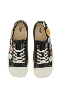 Moschino women’s black sneakers with white rubber soles and decorative smiley face and heart buttons
