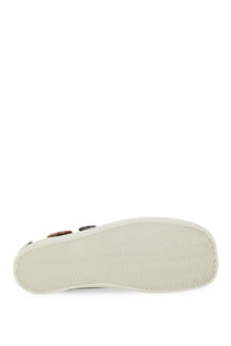 White rubber sole with herringbone tread pattern of moschino women’s black sneakers close up view