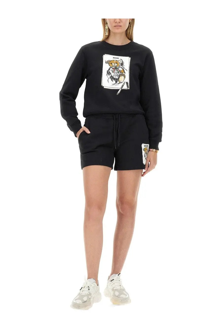 Moschino women’s black sweatshirt and shorts set with cartoon bear graphic on chest and patch detail on leg