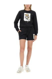 Moschino women’s black sweatshirt and shorts set with cartoon bear graphic on chest and patch detail on leg