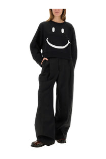 Black long-sleeved sweatshirt with bold white smiley face graphic on chest paired with moschino women’s tailored pants black