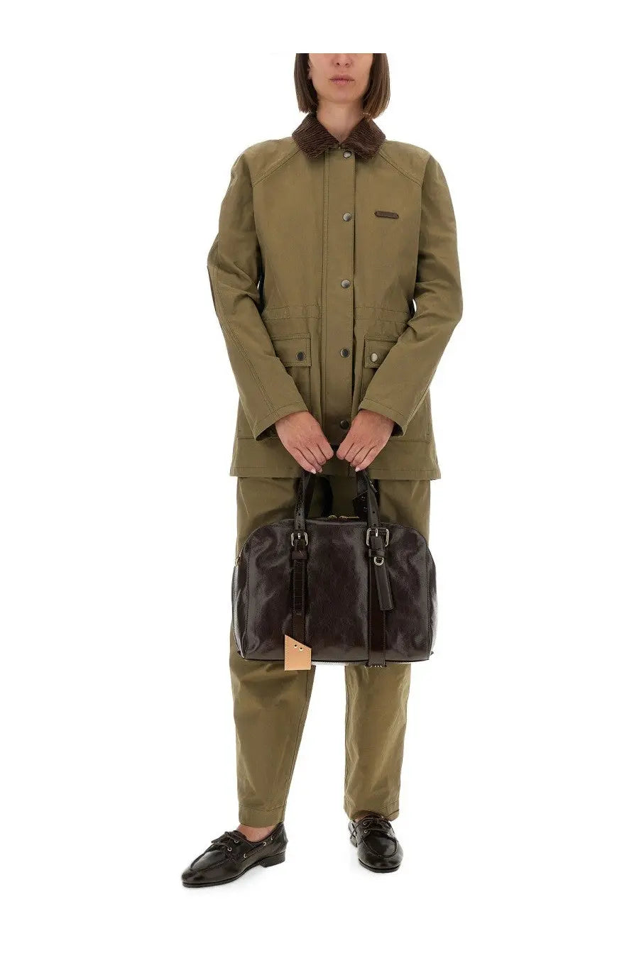 Black leather duffel bag with dual top handles and tan tag paired with moschino women’s tailored green pants
