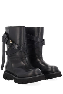 Moschino women’s black leather combat boots with thick soles and crisscrossing straps for edgy style