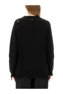 Moschino women’s black wool jersey knitted sweater with distressed ripped details on shoulders and hem