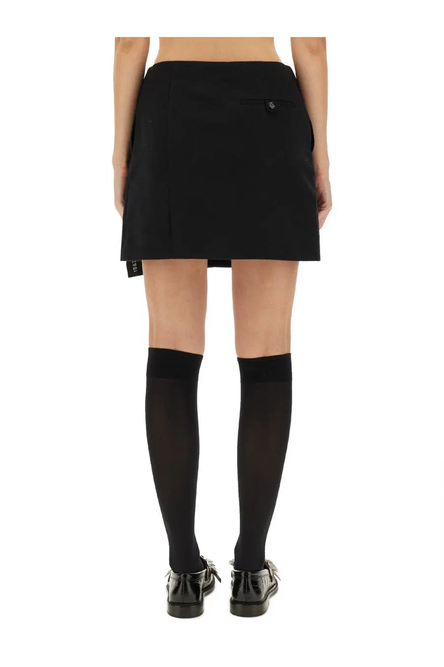Back side of moschino women’s black wool pleated mini wrap skirt with buttoned back pocket and brand tag at hem