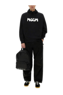 Black msgm backpack with white logo on front and side made of durable fabric paired with men’s black hoodie